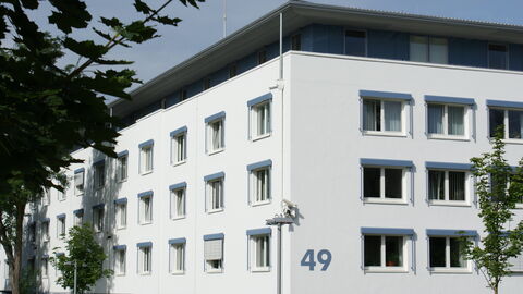 Außenansicht des Gebäudes des LfV Hessen. Auf dem Bild sieht man ein mehrstöckiges weißes Bürogebäude 