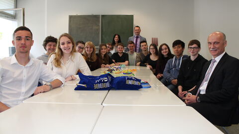 Schülerinnen und Schüler trafen in der Modellschule Obersberg in Bad Hersfeld auf LfV-Präsident Robert Schäfer (r.).Die Personen sitzen in einem Halbkreis um einen weißen Tisch.