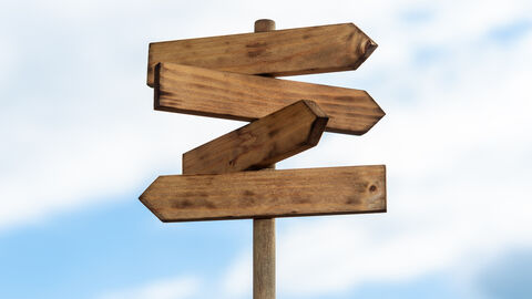 Bild eines Wegweisers, der in verschiedene Richtungen zeigt. Im Hintergrund sieht man einen blauen Himmel mit weißen Wolken