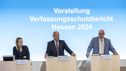 LfV-Präsident Bernd Neumann, Innenminister Roman Poseck und die Pressesprecherin des Innenministeriums bei der Vorstellung des Jahresberichts 2024 des LfV Hessen im Hessischen Landtag